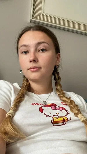 Woman with braided hair wearing white Hello Kitty t-shirt indoors.