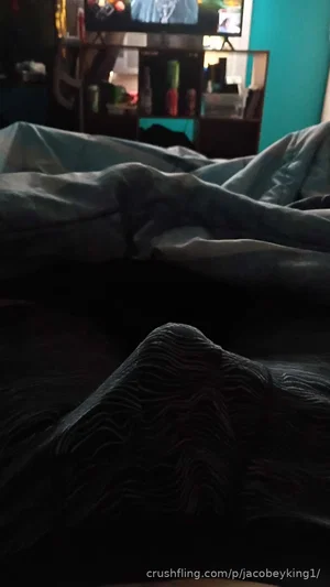 Dark bedroom scene with crumpled blankets, no person visible.