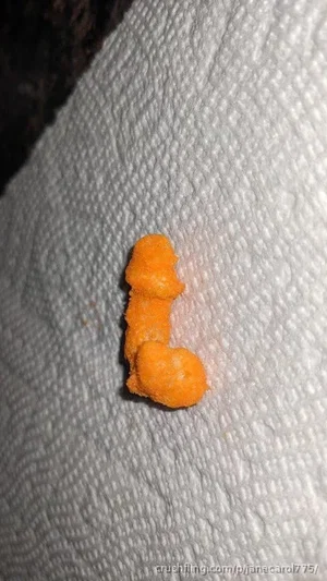 Orange food piece on white paper towel surface.
