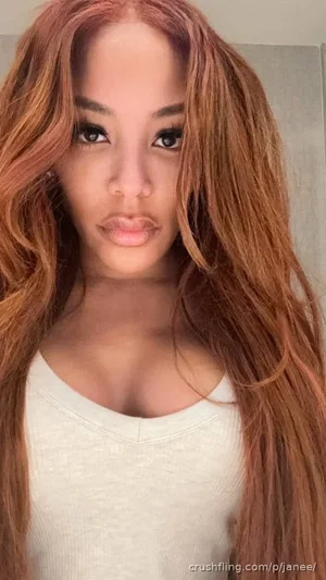 Woman with long wavy hair wearing a white top, indoor selfie.