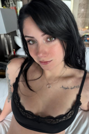 Woman with dark hair in black lace bra in bedroom.