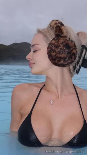 Woman in black bikini top with leopard earmuffs, standing in water outdoors.