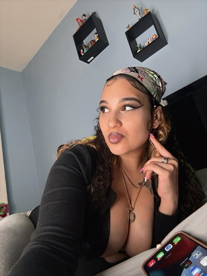 Woman with curly hair and bandana in black top taking selfie.
