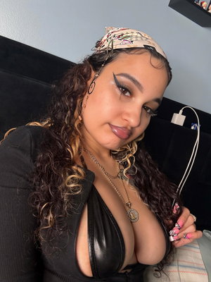 Woman with curly hair wearing black top and headscarf indoors.