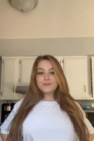 Woman with long blonde hair in white t-shirt in kitchen.