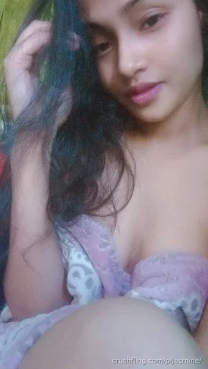 Woman with dark curly hair in a purple lace top, posing indoors.