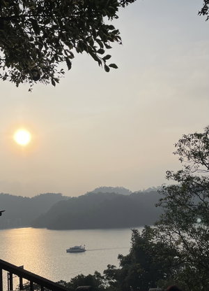 Sunset over lake with boat and forested hills from viewpoint.
