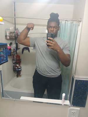Muscular Black man flexing in bathroom mirror selfie