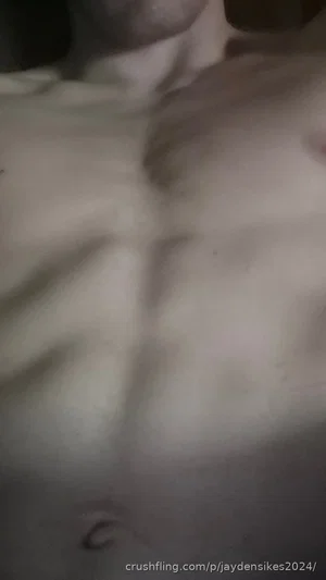 Shirtless man with defined chest and abdominal muscles, indoor setting.