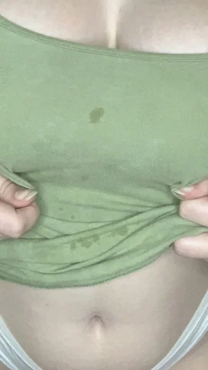 Woman in green top lifting fabric to show midriff, white underwear visible.