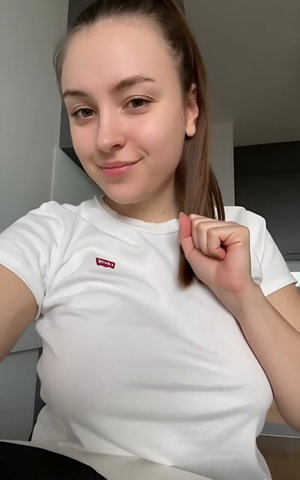 Slim woman with ponytail in white t-shirt indoors.