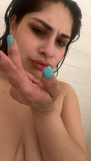 Woman with wet dark hair and turquoise nails in bathroom.