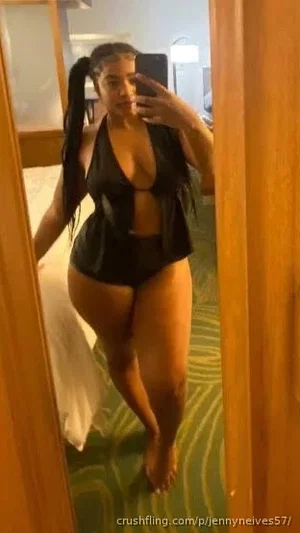Woman in black lingerie posing in mirror selfie in hotel room.