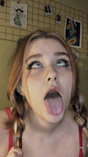 Woman with braided hair in red top making face indoors.