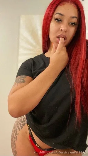Woman with red hair, black t-shirt, red underwear, tattoo on hip, indoors.