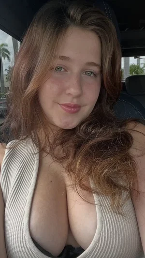 Curvy woman in low-cut top taking selfie in car