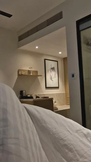 Bedroom interior with white striped bedding, modern decor, and adjacent bathroom visible.