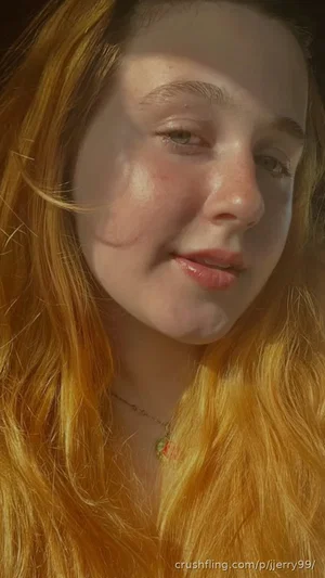 Woman with long blonde hair, wearing a delicate necklace, in warm lighting.