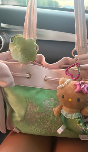 Pink and green handbag with Hello Kitty charm inside car.
