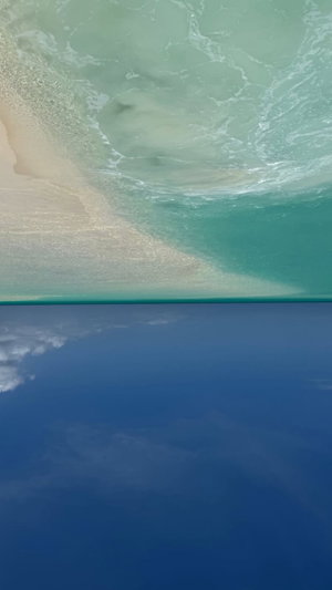 Aerial view of turquoise water meeting sandy beach under blue sky.