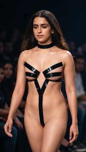 Slim woman in black tape outfit on runway.