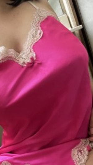 Woman in pink lace-trimmed satin lingerie, indoor setting.