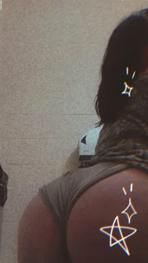 Woman in olive shorts, back view, sitting on tiled floor with digital sparkles.