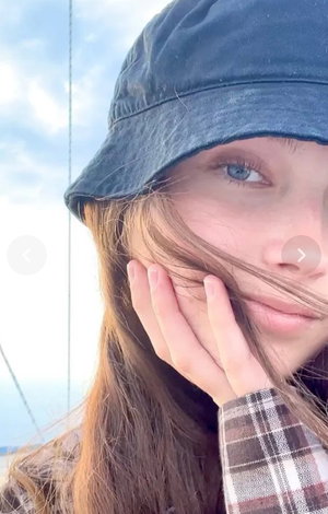 Woman in blue hat and plaid shirt posing outdoors.