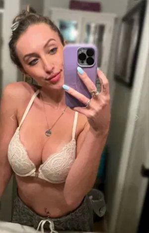 Woman in lace bra taking mirror selfie indoors.