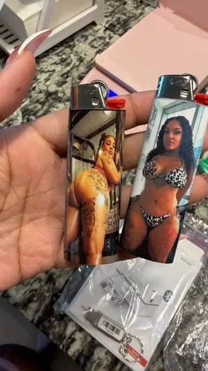 Hand holding two lighters with images of women in lingerie, one showing backside with tattoo,