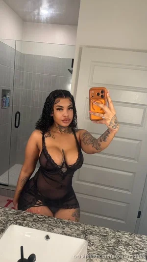 Woman in black lace lingerie taking mirror selfie in bathroom.