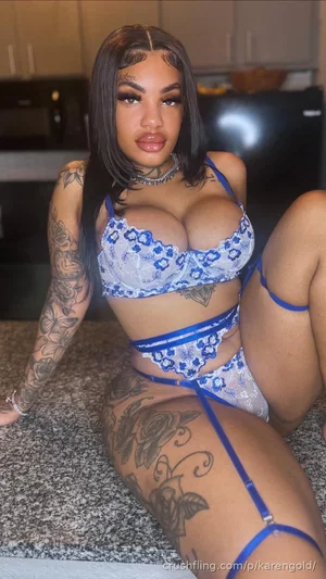 Woman in blue lace lingerie with tattoos posing on kitchen counter.