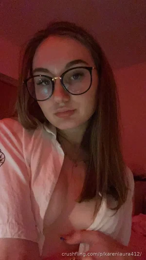 Woman with glasses in white shirt, indoors, holding collar open.
