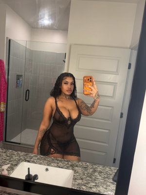 Woman in black lace lingerie takes mirror selfie in bathroom.