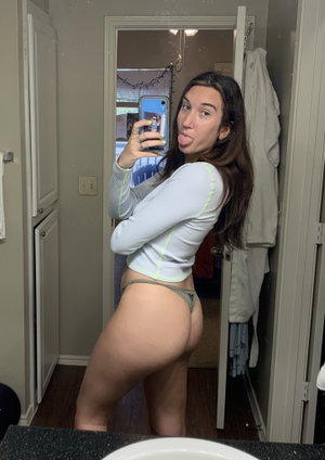 Curvy woman in blue top and panties taking mirror selfie.