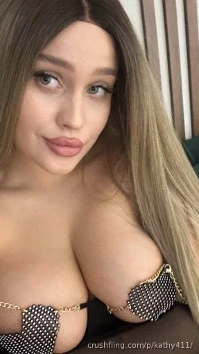 Woman with long hair in black studded lingerie, indoor selfie.