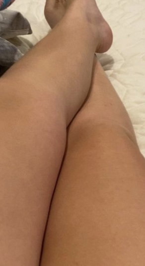 Legs resting on white bedding in bedroom.