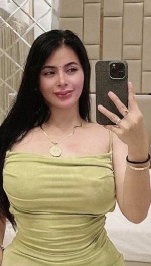 Curvy woman in green dress, bathroom mirror selfie.