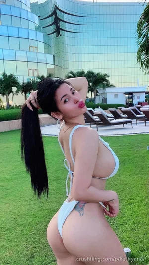 Woman in white bikini posing on grass near modern building, outdoor setting.