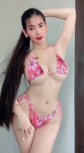 Woman with long dark hair in pink bikini posing indoors.