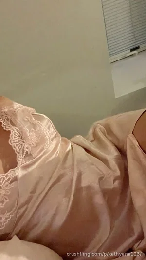 Woman in pink satin lingerie with lace trim, lying indoors.