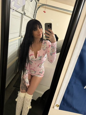 Woman with long black hair in pink patterned bodysuit and white knee-high socks taking mirror