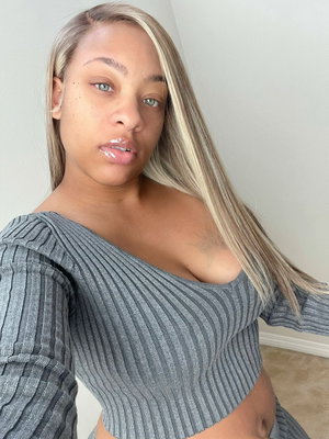 Woman with blonde hair in grey off-shoulder top taking indoor selfie.