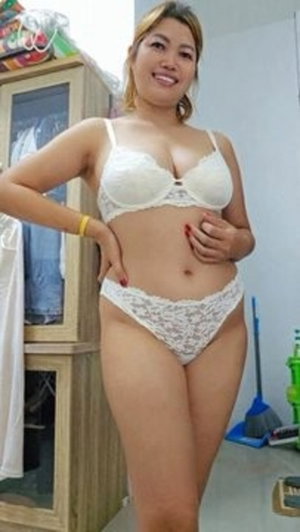 Woman in white lace lingerie posing indoors near a cabinet.