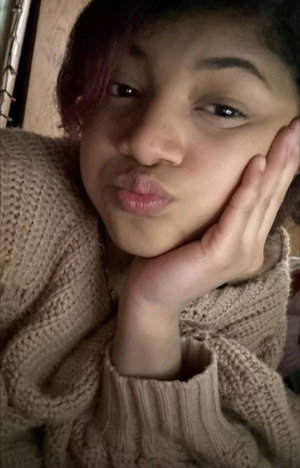 Asian woman with purple hair in knitted sweater, indoor selfie.