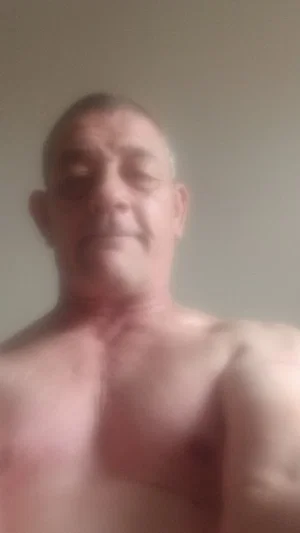 Shirtless man with short hair and visible chest, indoors, blurry image.
