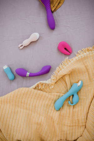 Colorful sex toys arranged on purple and yellow fabrics.