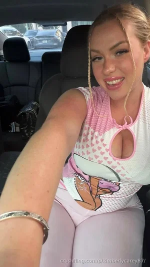 Woman in pink and white heart-patterned top with cutout, light pink leggings, sitting in car.