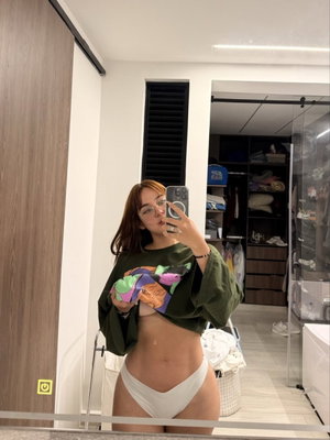 Curvy woman with glasses taking mirror selfie in bedroom.