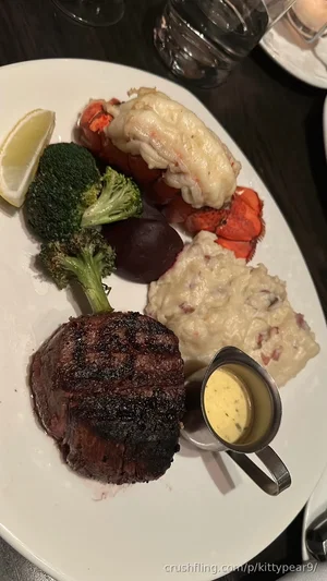 Plate with steak, lobster, broccoli, potatoes, and sauce on a dark table.
